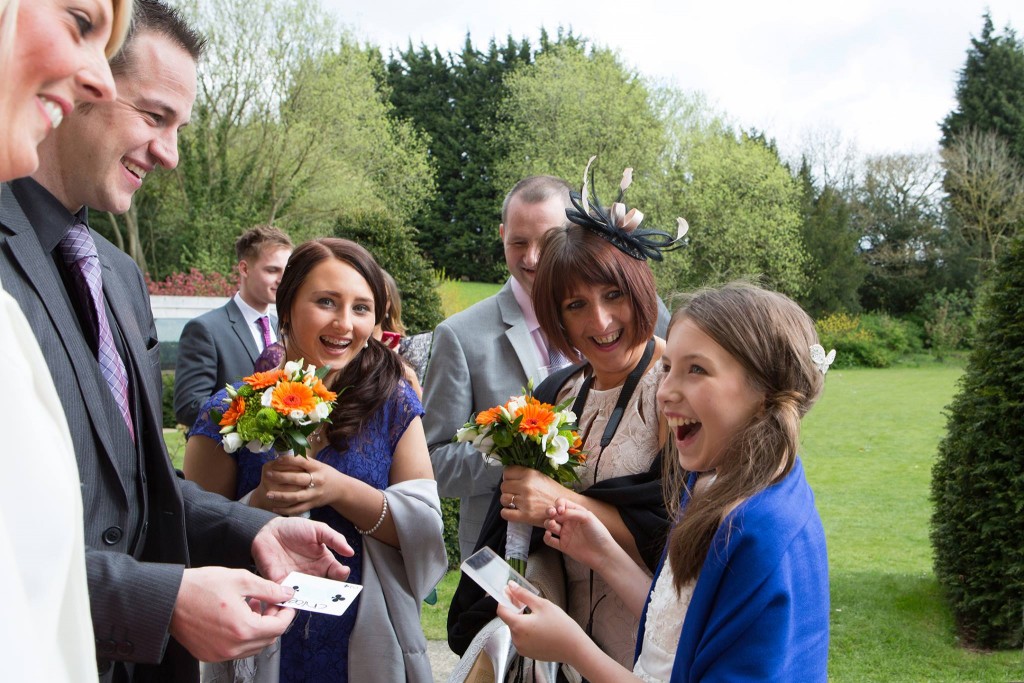Bridesmaids and family reacting to card magic in garden